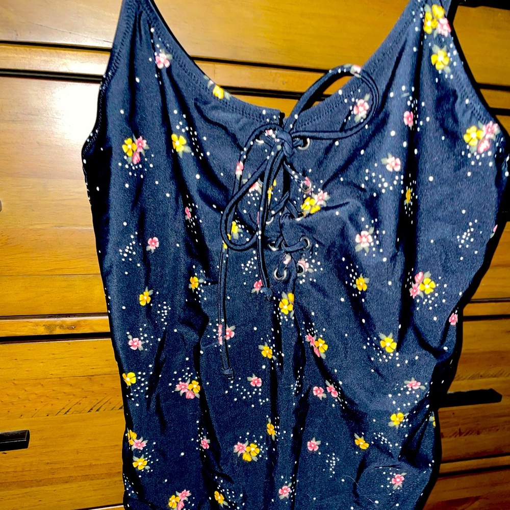 Black one-piece floral detail swimsuit with lace-up chest design.